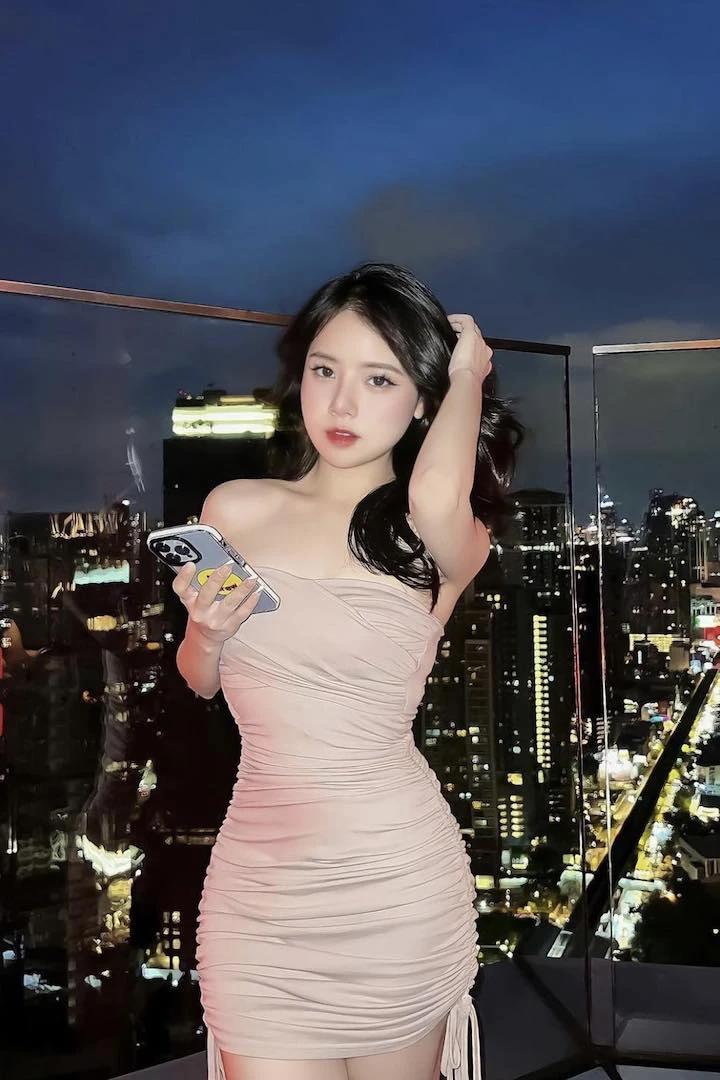 a beautiful asian girl in a tight dress is posing at octave rooftop bar in bangkok