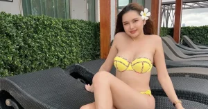 The beautiful Thai model Atommie smiling in a yellow bikini.