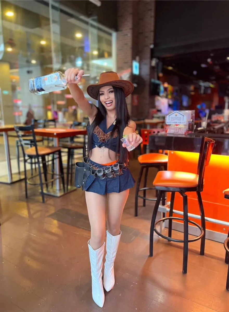 A gorgeous girl posing with a bottle and a shooter at Hooters Bangkok.