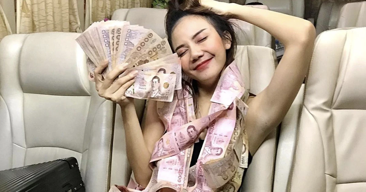Thai girl holding Thai baht bank notes in her hands and around her neck in a vip minivan
